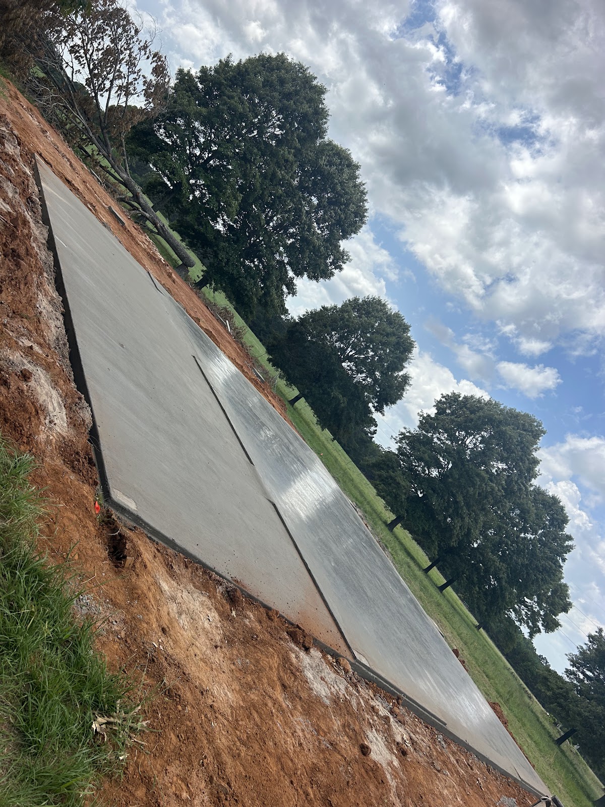 Large finished concrete slab under open sky and trees